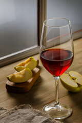 Glass of red wine and apples on wooden background, copy space
