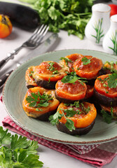 Eggplants and tomatoes baked with suluguni cheese and garlic served on a plate on a light gray background