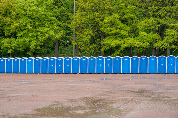 A row of portable toilets in front of a forest..
