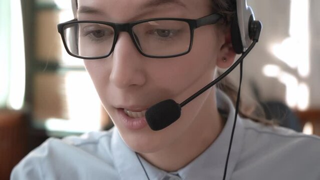 A girl in headphones with a headset conducts consultations. Call center. 