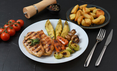 Barbecue chicken steak fried potatoes and vegetables on dark background