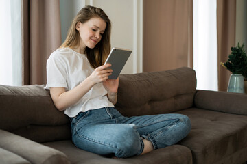 Uses a tablet app and an internet site. Young female freelancer online learning education at home.