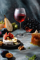 glass of red wine with grape, figs, honey, pears and camembert