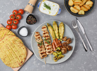Serving of grilled chicken with vegetable garnish and potatoes. BBQ food background