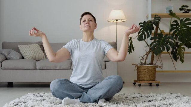 Senior woman doing meditation exercise stretching sports yoga. Mature healthy woman workout at home, exercise, fit, doing yoga, home fitness concept