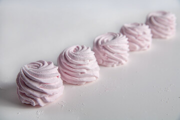 There is a pink marshmallow on the table. On a white background. Selective focus.