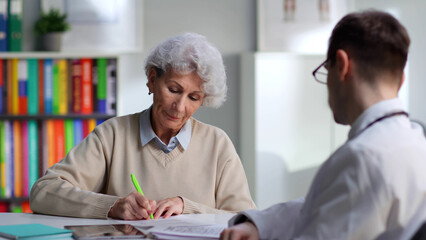 Elderly female patient sign medical service contract in doctor office