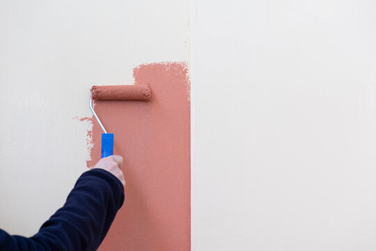 Manos con rodillo aplicando pintura a la madera