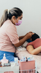 Fototapeta premium Latin American woman with beauty practice giving an eyelash treatment to a client.