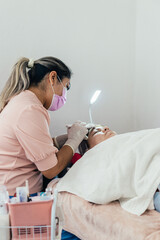 Doctor in an office performing acne treatment on her patient.