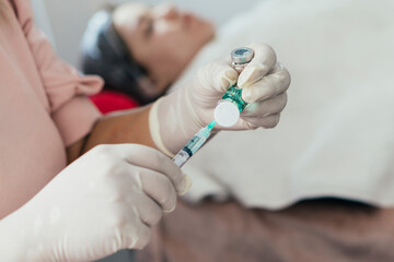 Doctor with syringe and mouthpiece and gloves applying a beauty treatment to a client on a...