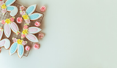 Fototapeta na wymiar Gingerbread cookies in the shape of cute Easter bunny ears decorated with festive icing and flowers on the white background. Flat lay