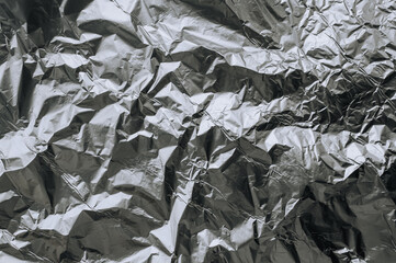 Background, texture of silver shiny foil, colored crumpled paper for packing goods. Close-up photo, top view, copy space.