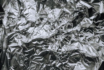 Background, texture of silver shiny foil, colored crumpled paper for packing goods. Close-up photo, top view, copy space, abstraction.