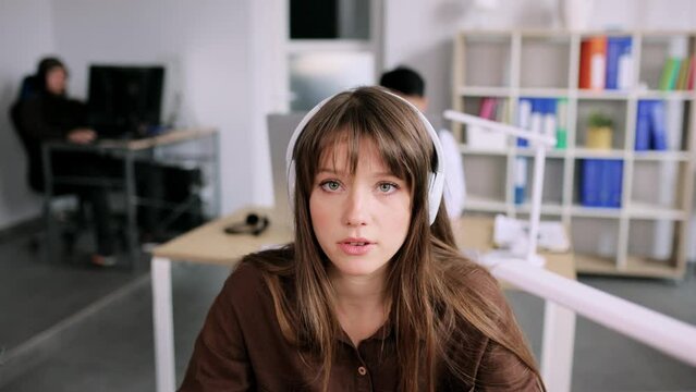 Young attractive woman have a video call while sitting on the chair in the office. Young lady talking on video conference online indoors. High quality 4k footage