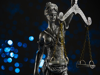 Bronze figurine of Themis - the goddess of justice on a blue background with twinkling lights. Symbol of law, justice, independence. The rule of law. Close-up.
