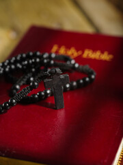 Macro shot. On the book of the Holy Bible are a rosary with a cross. Minimalism. Holy scripture, symbols of religion, catholicism, spirituality and faith. Jesus Christ, crucifixion.