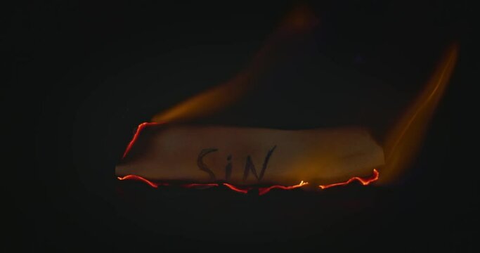 Closeup video of burning paper with SIN written on it
