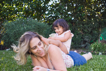 Little girl climbed on the back of a woman in the grass