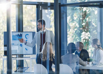 Teamwork divides the task and multiplies the success. Shot of a businessman presenting information on a monitor in the office to a group of businesspeople.