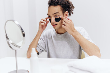 guy with curly hair with patches on the face sit in front of the mirror light background