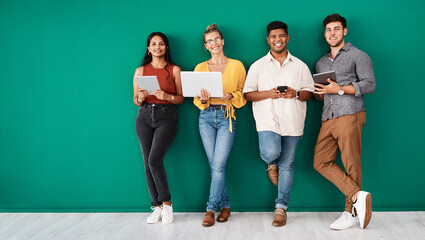 Were always in the loop. Portrait of a group of young designers using digital devices while standing together against a green background. - Powered by Adobe