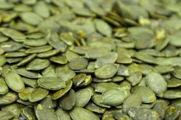 Background texture of green pumpkin seeds. Organic food, selective focus.