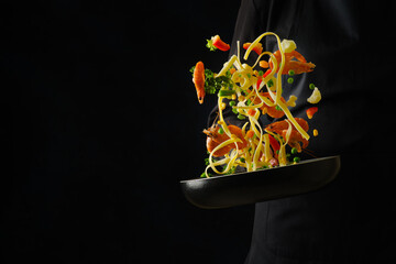 Colorful assorted seafood, vegetables, herbs and italian pasta in a pan in frozen flight on a black background. Seafood, Italian cuisine. Recipes for restaurant and home cooking. Advertising, banner.