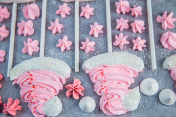 Meringues in the form of pink Christmas hats with a pompom and a white lapel on a stick lie on...