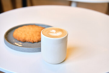 Morning brunch in cafe is on table. Giant cookie and cappuccino with beautiful milk foam. Sometimes you gotta pause in this fast paced world