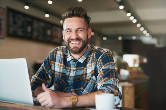 I like my internet connection as strong as my coffee. Portrait of a young man using his laptop while sitting by the window in a cafe.