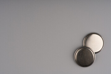 Round batteries on a gray background. Closeup. Space for text