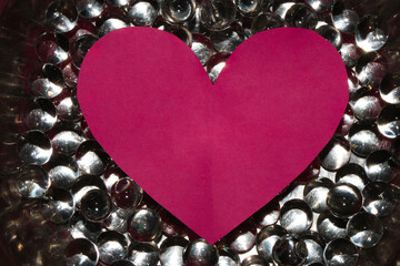 
abstract liquid silver background with a futuristic look, on it a pink paper heart as a copy space