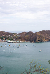 Fototapeta premium vertical format aerial view of a beach full of tourists, beach surrounded by mountains.