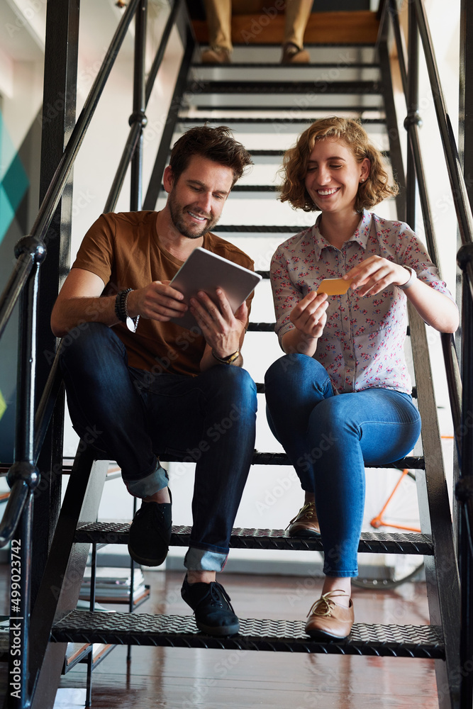 Poster Collaboration gives the best results. Shot of two designers discussing something on a tablet while sitting on a staircase.