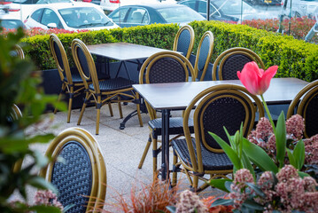 Clean empty tables and chairs at outdoor cafe restaurant in England surrounded by plants and flowers.