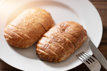 Serving of two ham and cheese pies on a white plate on wooden table. Simple food concept. Pastry product for lunch.