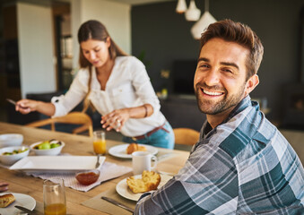 We share every meal together. Portrait of a man having breakfast with his wife in the background.