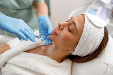 Fototapeta na wymiar Young woman receiving hyaluronic acid injection in beauty salon. Cosmetology