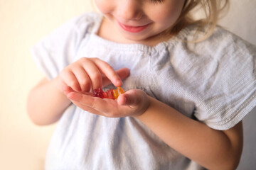 small child, blonde girl 3 years old wants to eat gelatinous sweets, gummy bear, kid has a good...