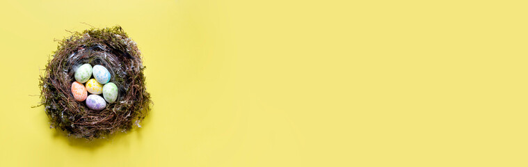 on a yellow background, Easter eggs in bed tones of different colors in a nest