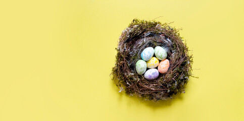 on a yellow background, Easter eggs in bed tones of different colors in a nest