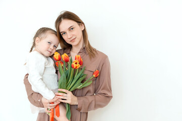Fototapeta na wymiar Happy daughter congratulates mom with tulips. Portrait. Looking at camera