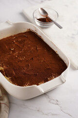 Step by step process of preparing italian dessert tiramisu out of ladyfinger biscuits, mascarpone cheese, espresso on white marble background