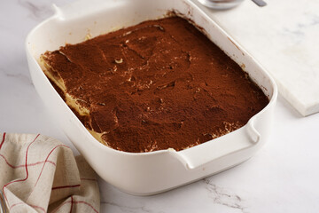 Step by step process of preparing italian dessert tiramisu out of ladyfinger biscuits, mascarpone cheese, espresso on white marble background