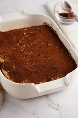 Step by step process of preparing italian dessert tiramisu out of ladyfinger biscuits, mascarpone cheese, espresso on white marble background