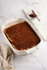 Step by step process of preparing italian dessert tiramisu out of ladyfinger biscuits, mascarpone cheese, espresso on white marble background