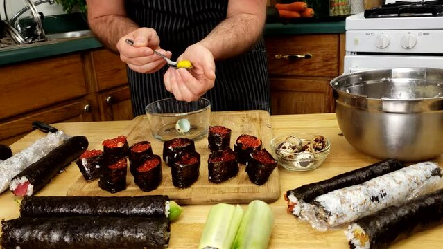 Home cooking - Preparing battleship sushi using rice, salmon caviar, quell egg yolk and  nori as wrapping.