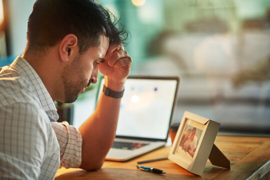 Who Will Look After Them When Im Gone. Shot Of A Worried Businessman Looking At A Picture Of His Family While Sitting At His Desk.