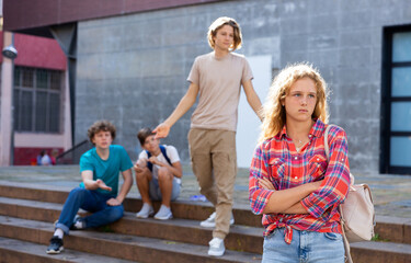 Upset girl in front of her friends after quarrel on the street